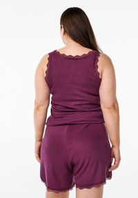 Top a senza maniche di colore viola scuro con bordi in pizzo a scallop, abbinato a pantaloni corti coordinati con dettagli in pizzo simili all'orlo.