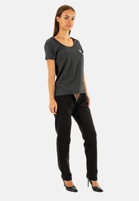 Top de manga corta a rayas en blanco y negro, combinado con pantalones negros y tacones altos. Presenta un escote redondeado y un corte relajado.