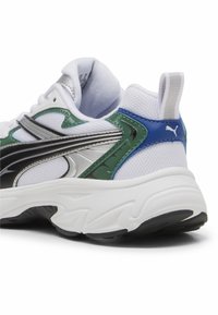 Sneaker bianco con accenti verdi, neri e blu. Presenta una tomaia in rete testurizzata, collo imbottito e una suola spessa bianca con dettagli neri.