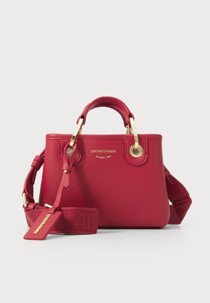 Red textured handbag with gold hardware, dual top handles, and a detachable strap with logo detailing. Compact design with round shape.