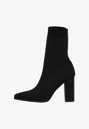 Schwarzer gestrickter Knöchelboot mit spitzem Schuhkopf, geripptem oberen Teil und dicker Absätze. Glatte Textur mit einem eleganten, körperbetonten Design.