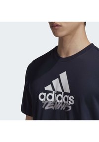 Námořnická modrá pánská bavlněná trička s krátkým rukávem, na přední straně s výrazným bílým logem Adidas a grafikou "TENNIS" v stylizovaném písmu.