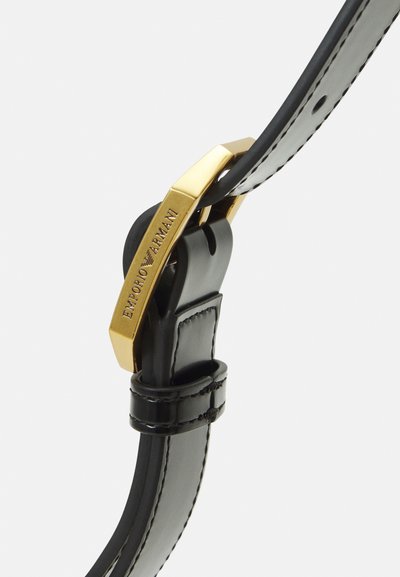 Musta nahkavöö sileda viimistlusega, millel on kuldse tooni ristkülikukujuline klamber, millel on sõna "EMPORIO ARMANI" reljeefne kiri. Elegantsed õmbluse detailid.