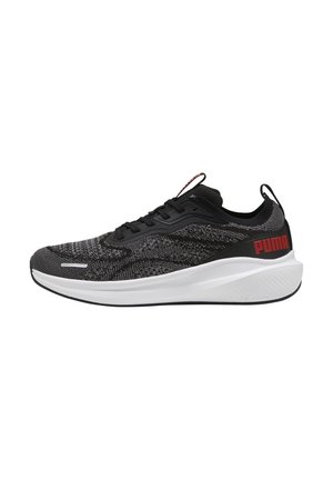 Baskets tricotées noires et grises avec une semelle intermédiaire blanche, présentant un dessus texturé, des lacets noirs et un logo rouge bien visible sur le talon.