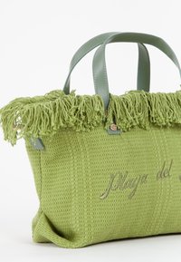 Borsa verde intrecciata con una parte superiore frangiata, manici robusti e testo ricamato. Accenti in pelle liscia completano il tessuto testurizzato.