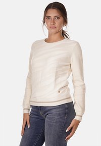 Maglione color crema con un motivo a onda testurizzato, scollatura rotonda e polsini e orlo a costine. Presenta un piccolo logo decorativo vicino al fondo.