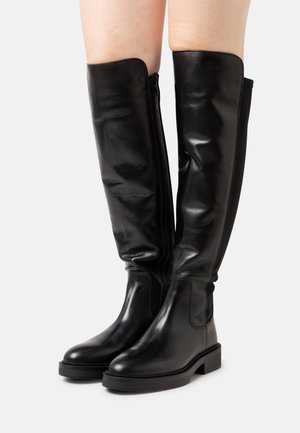 Botas de cuero negro por encima de la rodilla con una textura suave, cierre lateral y un tacón ancho. Presenta un diseño ajustado por encima de los tobillos.