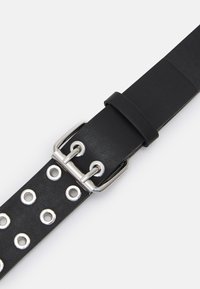 Cinto de couro preto com hardware prateado, fivela retangular e ilhós metálicos redondos ao longo do comprimento para ajuste de tamanho.