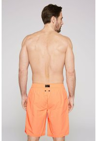 Oranžové plavky s elastickým páskem. Obsahují dvě zadní kapsy na knoflíky. Lehká látka se hladkým povrchem.