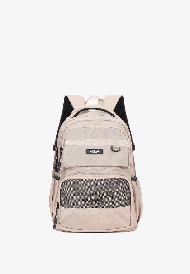 Zaino beige con più scomparti, dotato di una tasca frontale in rete, spallacci regolabili e un'etichetta con il logo. Il materiale è una tela resistente.