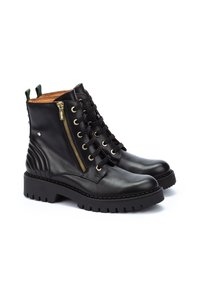 Bottines noires en cuir avec un laçage à l'avant et une fermeture éclair sur le côté. Présentent des éléments en métal doré, des accents côtelés et une semelle en caoutchouc épaisse.