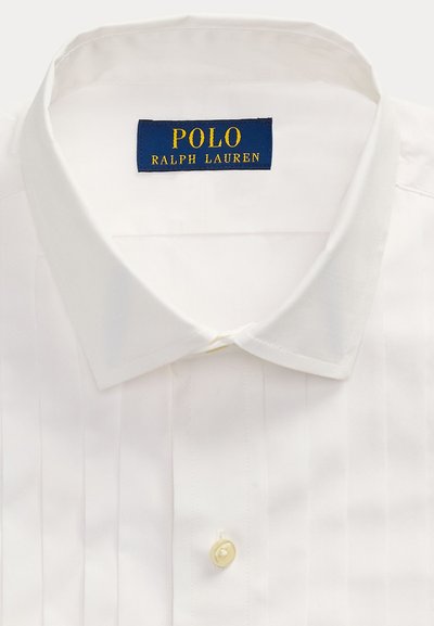 Camicia bianca con collo aperto e etichetta blu con scritta gialla "POLO RALPH LAUREN" all'interno del colletto.