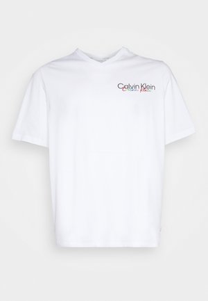Biała koszulka z krótkim rękawem i dekoltem w serek z małym, wielokolorowym logo "Calvin Klein" na lewej piersi.