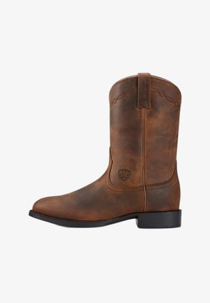 Bota de vaquero de cuero marrón con costuras decorativas, lengüeta para tirar, tacón bajo y suela de goma negra, vista lateral.