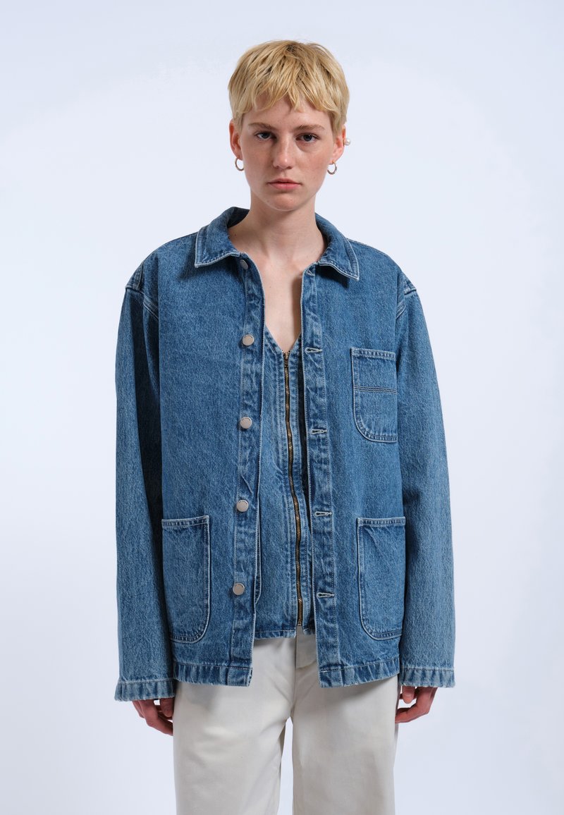 Giacca di jeans blu con chiusura a bottoni, colletto all'americana, due tasche frontali e maniche lunghe. Presenta cuciture leggere e una vestibilità comoda.