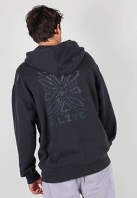 Hoodie noir en mélange de coton, avec un design graphique en couleur plus claire dans le dos. Comprend une capuche à cordon et des poignets côtelés.