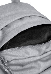 Mochila de tela gris con un suave interior negro. La apertura con cremallera revela un forro texturizado y suave para mayor protección.