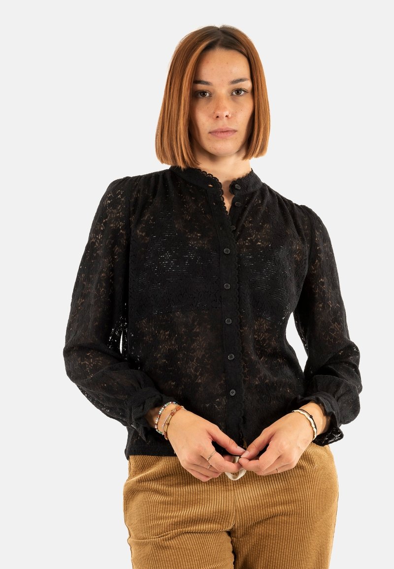 Blusa nera in pizzo con colletto rotondo, chiusura con bottoni e maniche lunghe. Presenta un motivo testurizzato e polsini con volant.
