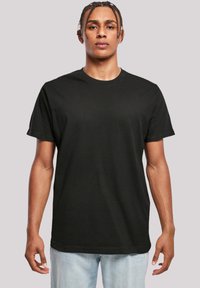 Schwarzes Baumwoll-T-Shirt mit Rundhalsausschnitt, kurzen Ärmeln und lockerem Schnitt, vor einem hellgrauen Hintergrund präsentiert.