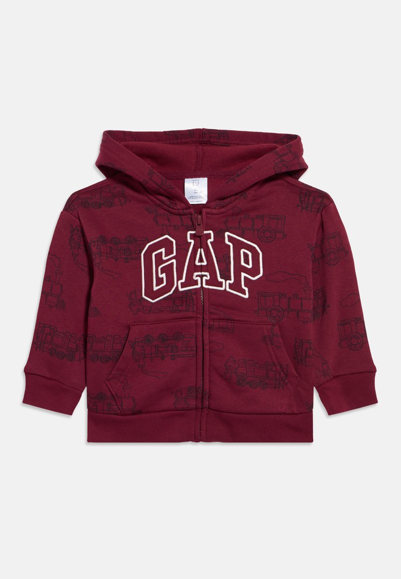 Gyermekek számára készült bordó cipzáras kapucnis pulóver vonatos mintával, elülső zsebekkel és a mellrészen nagy, fehér körvonalas "GAP" logóval.