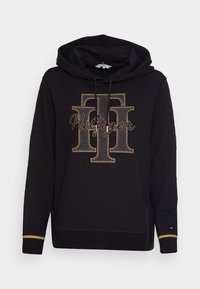 Sudadera negra con un diseño de logo de strass dorados, con capucha ajustable y acentos dorados en los puños, fabricada con tejido suave.