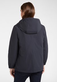 Giacca impermeabile blu navy scuro con cappuccio, polsini elastici e due tasche frontali. Texture morbida e design leggero, adatti per l'abbigliamento da esterno.