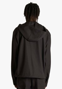 Giacca nera con cappuccio e vestibilità comoda, caratterizzata da una texture liscia, maniche lunghe e un design semplice. Nessun logo o motivo visibile.