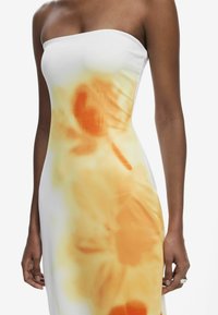 Strapless dress in white with an orange and yellow floral print. Smooth fabric with a fitted silhouette, featuring an abstract design.