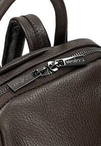 Borsa in pelle marrone con superficie testurizzata, chiusura con cerniera e elemento decorativo in metallo color argento, dotata di due manici arrotondati.