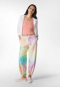 Outfit i bomuldsblanding bestående af en koralfarvet ribbet tanktop og pastelfarvede tie-dye joggingbukser med elastiske manchetter. Hvid zip-up hoodie og lyserøde sneakers.