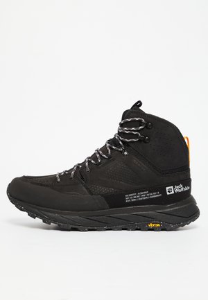 Zwarte wandelschoen met bovenwerk van mesh en suede, reflecterende veters, zachte tussenzool en Vibram-buitenzool voor grip en duurzaamheid.