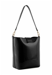 Bolso de mano de charol negro con un diseño estructurado, base plana, correa desmontable y un elegante asa superior. Presenta detalles en herrajes de tono dorado.