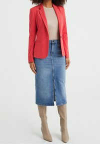 Roter Blazer, beiges Top, Denim-Midi-Rock mit Schlitz vorne und beigen kniehohen Stiefeln. Glatte Texturen und strukturierte Gestaltung.