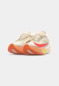 Nike Zoom Fly hardloopschoenen hebben een crèmewitte mesh bovenwerk, levendige roze en groene accenten, een geamoerd zool en een getextureerde oranje buitenzool.