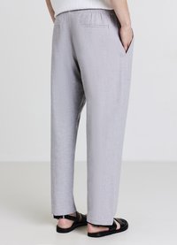 Hellgraue Hose mit elastischem Bund, Seitentaschen und glatter Textur. Das Design zeichnet sich durch gerade Beine und eine legere Passform aus.