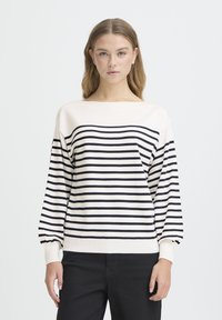 Pull-over rayé crème et bleu marine avec un col bateau, des manches longues et des poignets côtelés. Le matériau semble doux et tricoté.