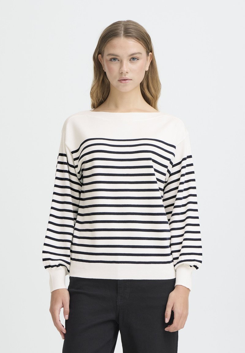 Pull-over rayé crème et bleu marine avec un col bateau, des manches longues et des poignets côtelés. Le matériau semble doux et tricoté.