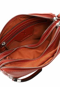Interno di una borsa a tracolla in pelle rossa con più scomparti. Presenta cerniere argentate, texture liscia e fodera arancione.