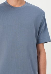 Blå crew-neck t-skjorte i et mykt, lett stoff. Har korte ermer og ribbet tekstur, med en avslappet passform.