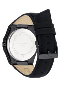 Zwarte roestvrijstalen horloge met een ronde kast, leren band en een heldere glazen achterkant. Bevat een gladde afwerking en witte branding.