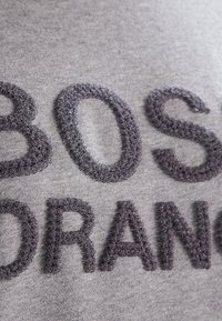 Sudadera de algodón gris con texto en relieve de color gris oscuro con textura peluda. El texto dice "BOSO ORANGE" en una fuente negrita y de bloque.