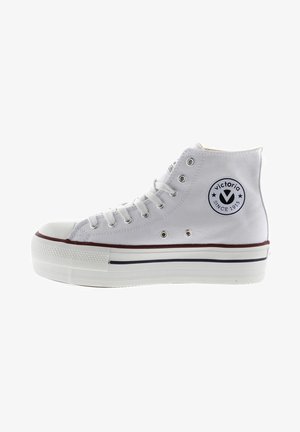 Witte hoge sneakers van canvas met een ronde neus, voorzien van een zwart circulair logo, vijf veterogen en een gestructureerde rubberen zool.