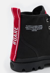 Stivale in tessuto nero con suola in gomma nera rigata. Presenta un tassello rosso con la scritta "#DARE" e cuciture. Logo laterale stampato in bianco.