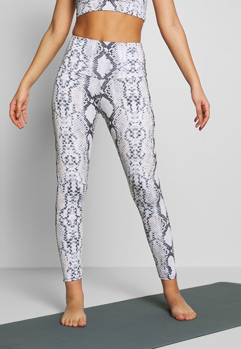 Svart och vit ormtryckta leggings med hög midja och åtsittande design, tillverkade av ett mjukt, stretchy material.