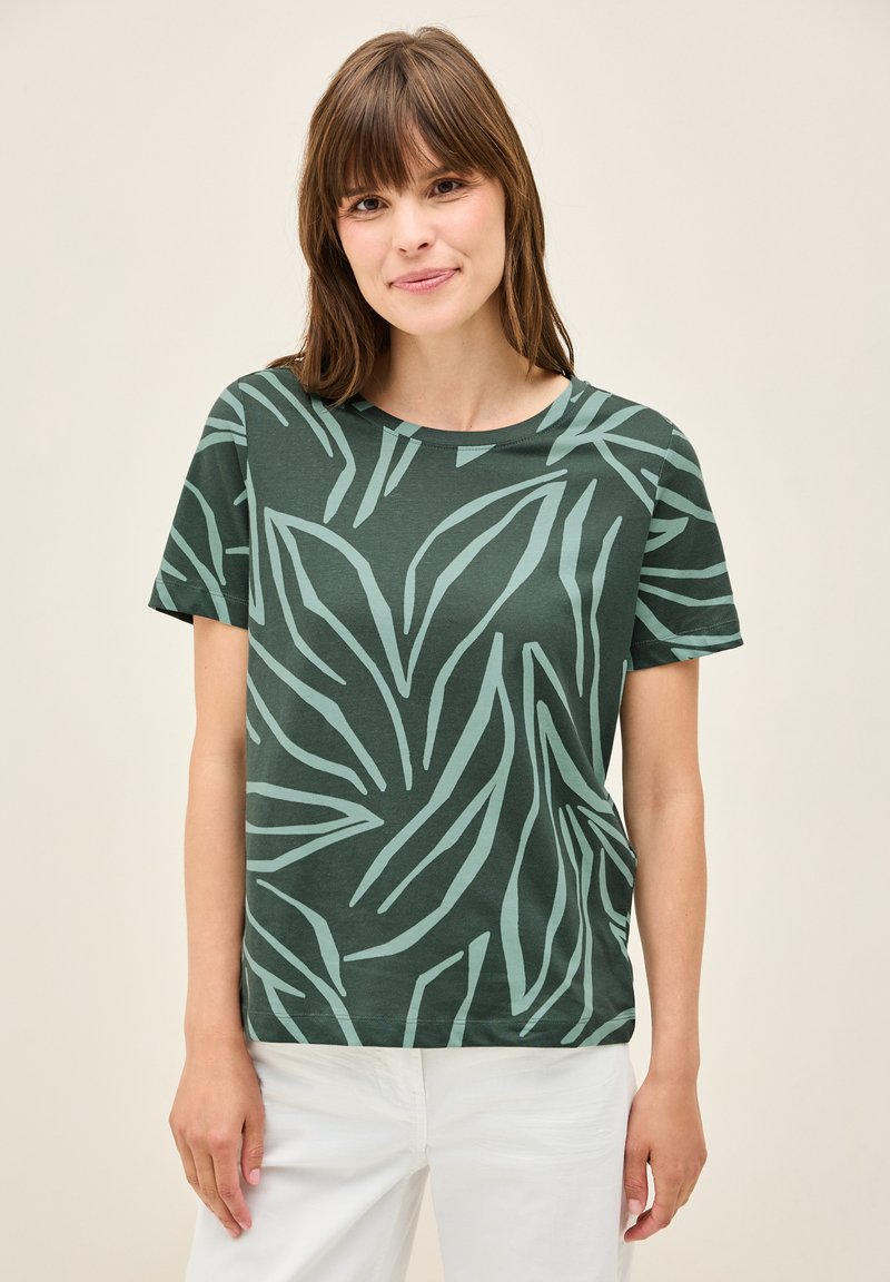 T-shirt verde a maniche corte con un motivo foglioso in verde chiaro. Presenta un collo rotondo e una vestibilità rilassata. Il tessuto appare morbido e liscio.