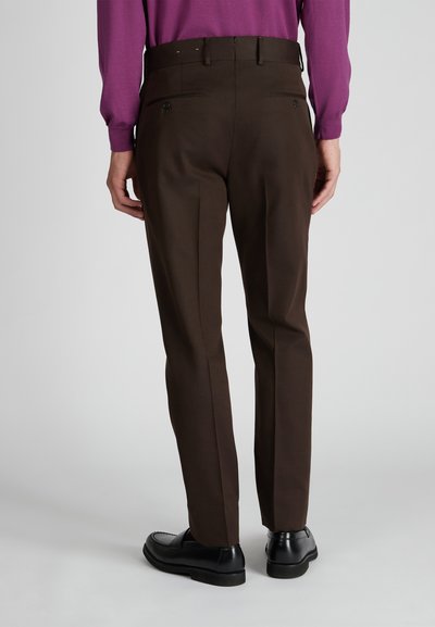 Pantaloni marroni con una vestibilità su misura, tasche posteriori singole e una texture liscia. Abbinati a mocassini neri e una camicia a maniche lunghe viola.