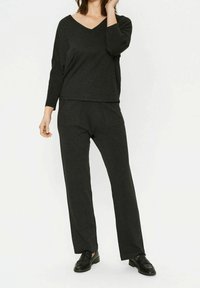 Tumma harmaa neuleasu, johon kuuluu V-pääntie, pitkähihainen paita ja löysät housut, joissa on etutaskut ja pehmeä pinta.