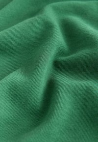 Green cotton fabric with a soft, textured surface, showcasing a smooth, draped appearance and fine ribbed patterns throughout.