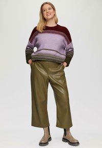 Gebreide trui in paars en bordeaux met gestreept patroon, gecombineerd met olijfgroene leren brede broek en beige enkellaarsjes.