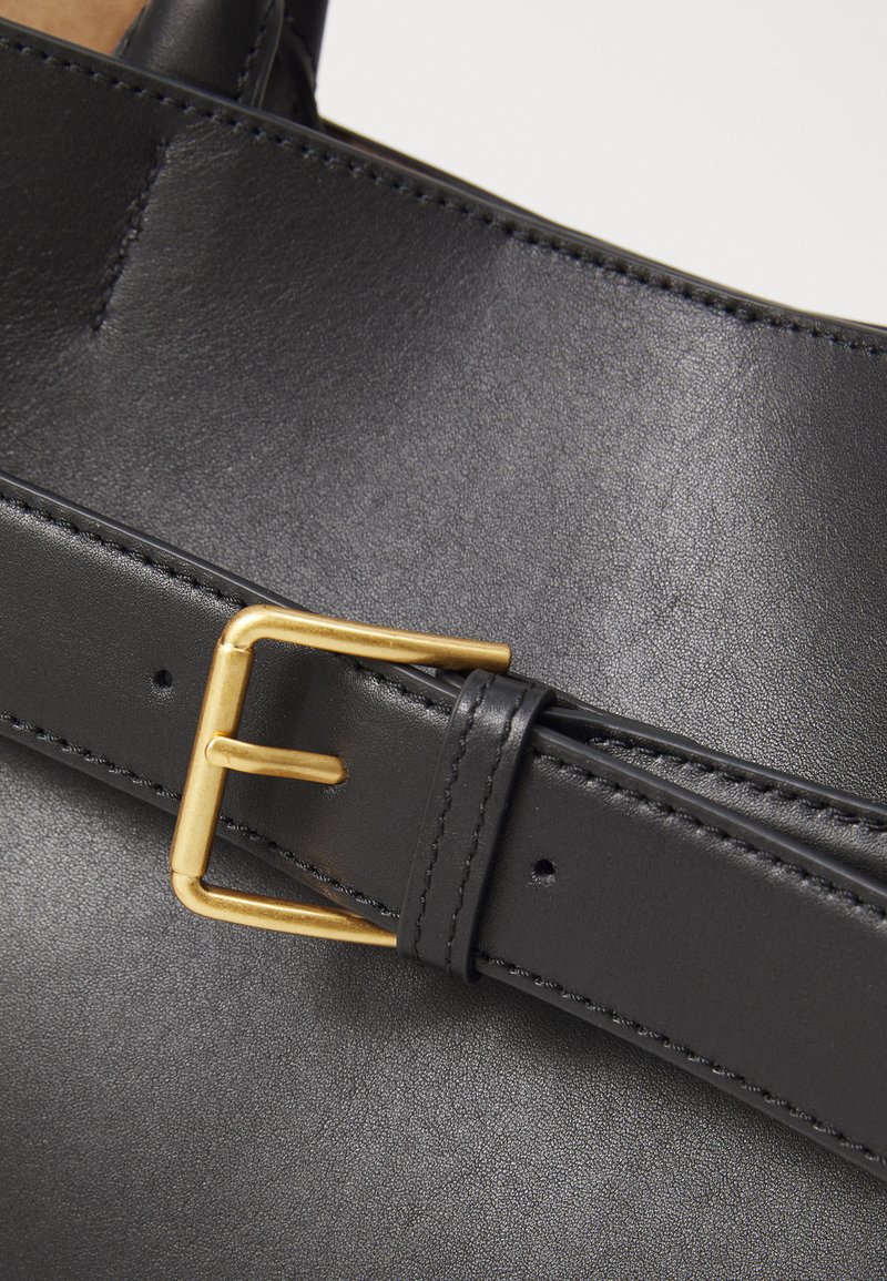 Svart läderrem med en guldmetalldolk och sömdetaljer. Remmen är slät med en något texturerad yta.